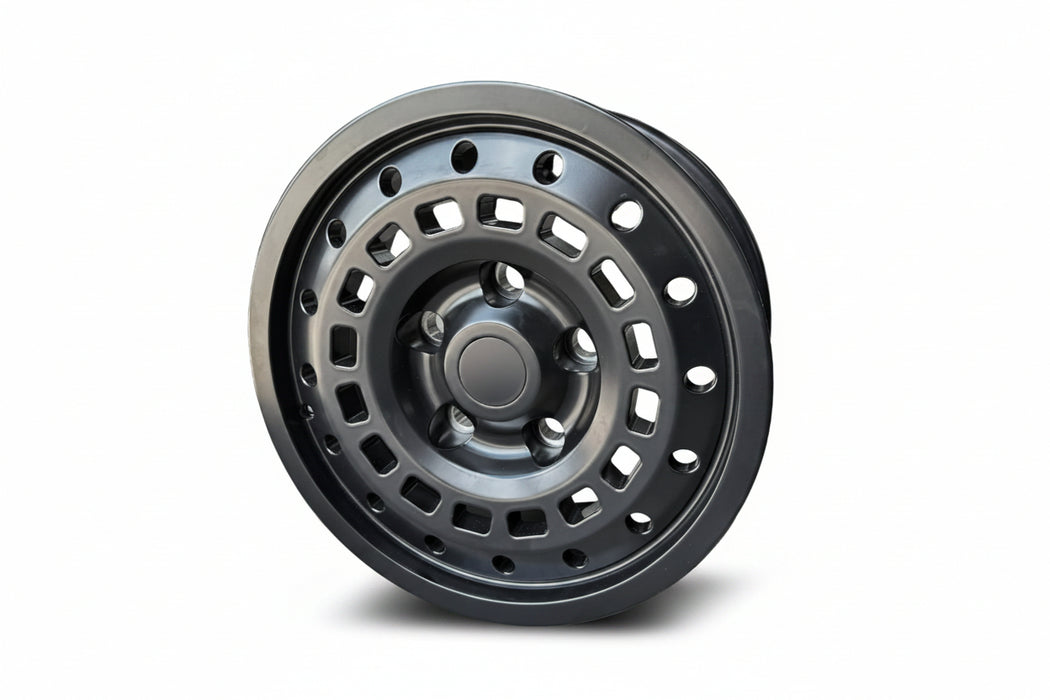 A matte black steel wheel rim with a multi-spoke, square-hole design, shown standing upright.